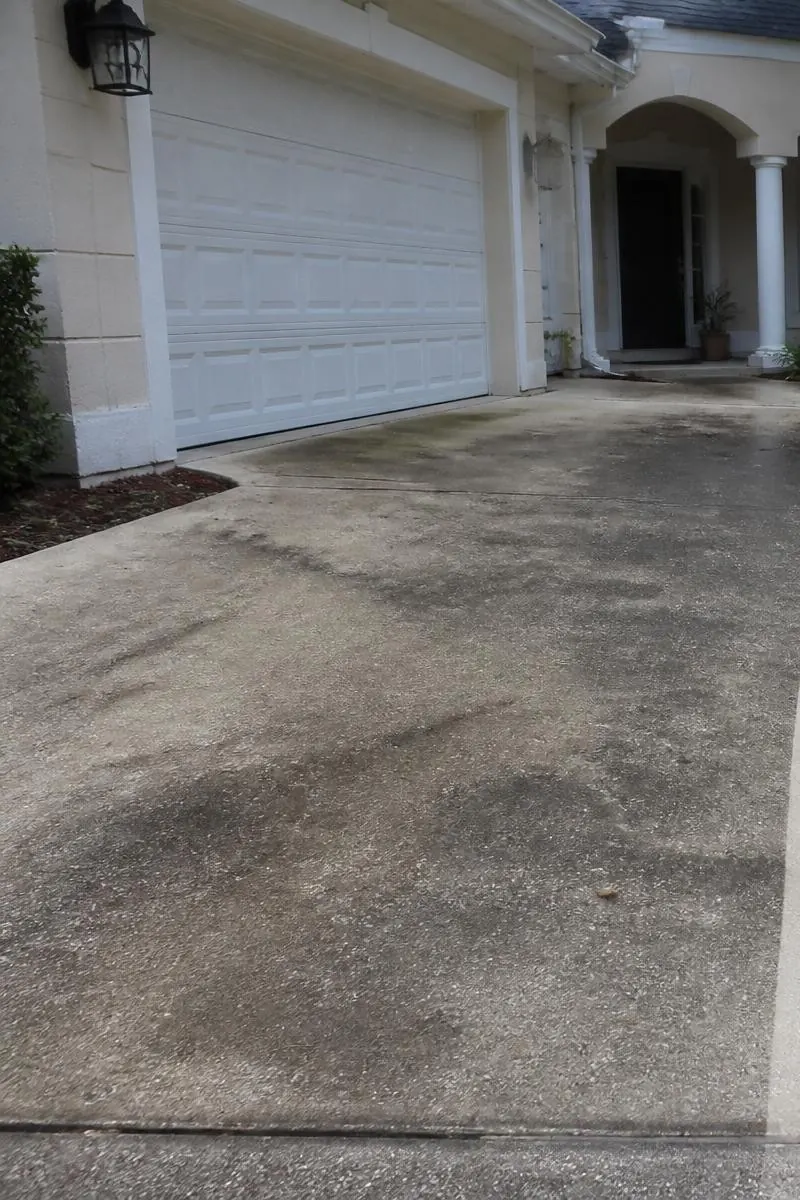 Stained, algae-covered concrete driveway before pressure washing in Volusia County, FL